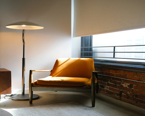 Cozy reading corner with warm lamp light next to a window in the evening